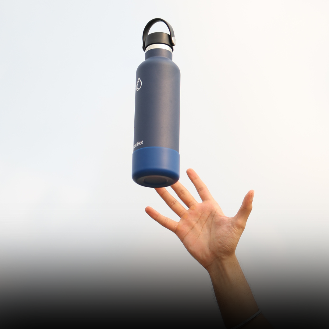 Close-up of a coffee filter and a black kettle on a table with people in the background.