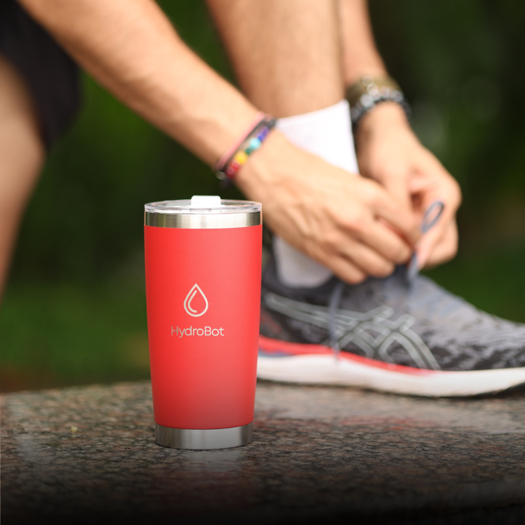 Hand pouring coffee from a black carafe into a glass.