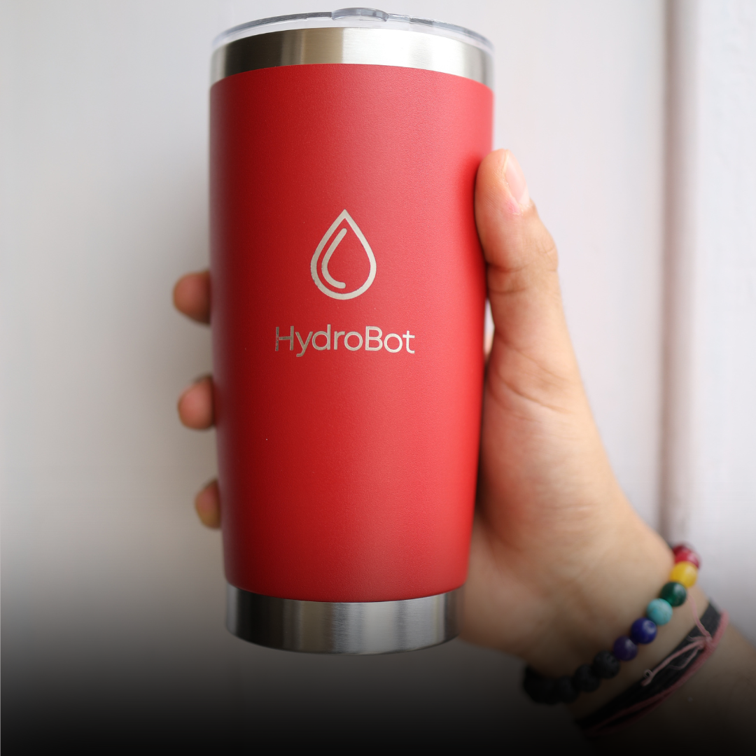 Close-up of a coffee filter and a black kettle on a table with people in the background.