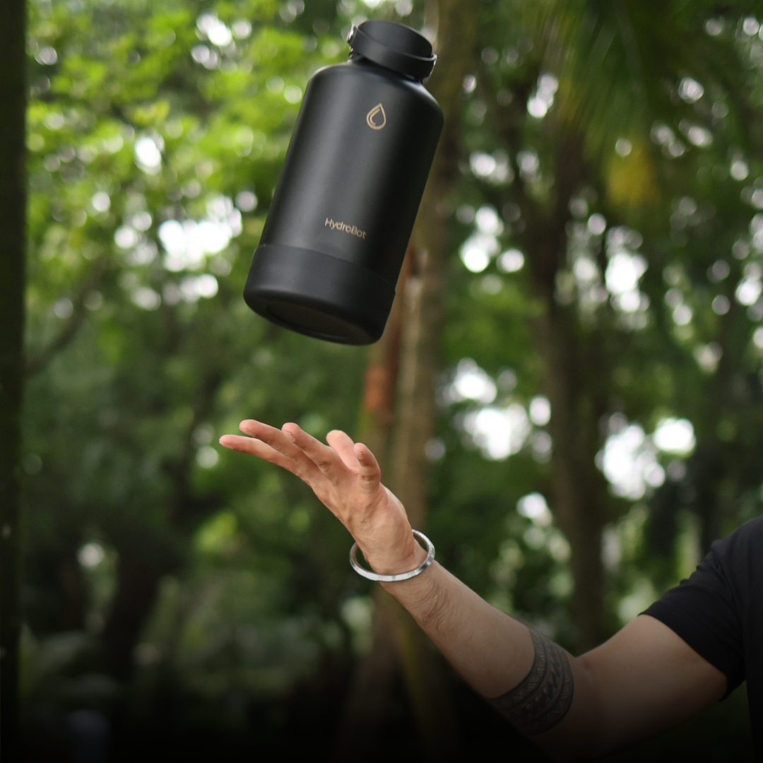 Close-up of a coffee filter and a black kettle on a table with people in the background.