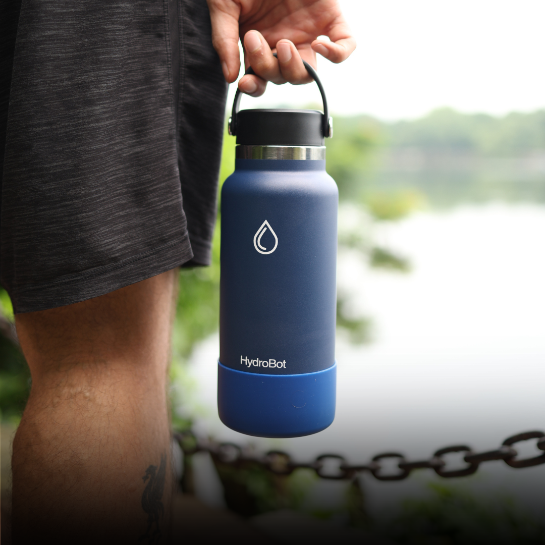 Close-up of a coffee filter and a black kettle on a table with people in the background.