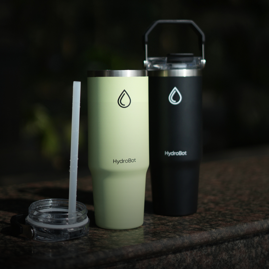 Close-up of a coffee filter and a black kettle on a table with people in the background.