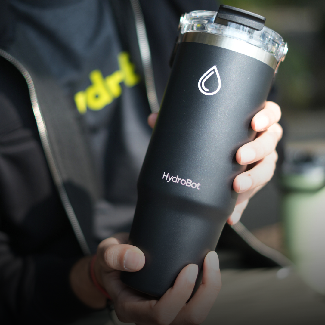 Hand pouring coffee from a black carafe into a glass.